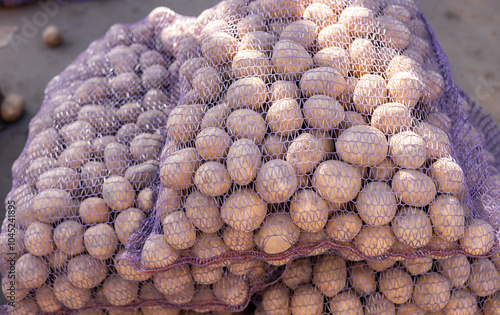 A vibrant scene of a pile of fresh potatoes in various sizes and colors, displayed in a farmer s market stall, surrounded by other fresh vegetables. photo