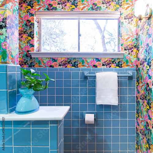 Stylish midcentury modern bathroom with floral wallpaper and blue tile.
