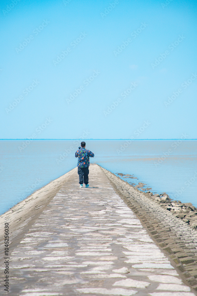 Hengsha Island, Shanghai - young man standing on the beach under the blue sky Hengsha Island, Shanghai - young man standing on the beach under the blue sky