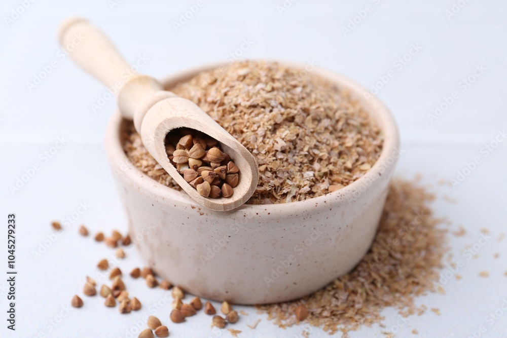Buckwheat bran in bowl and grains on white table, closeup Buckwheat bran in bowl and grains on white table, closeup