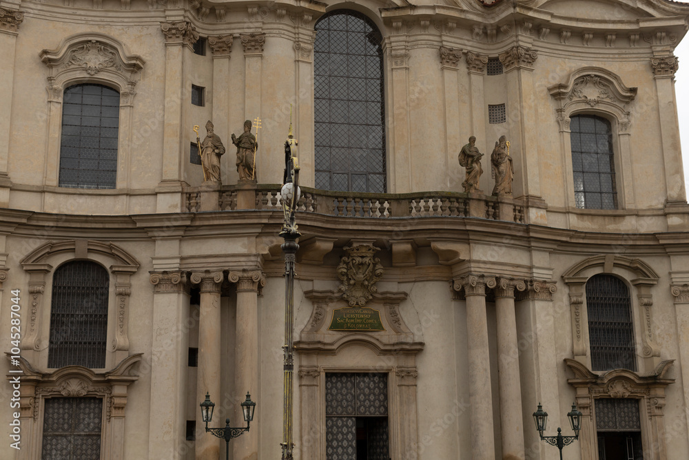 There is a very large structure that features a prominent balcony and also has several statues adorning its exterior design and facade There is a very large structure that features a prominent balcony and also has several statues adorning its exterior design and facade