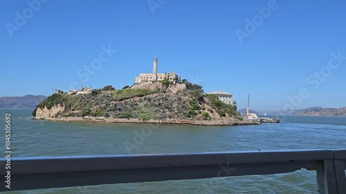 Alcatraz island and prison. View from a moving tourist boat, ferry. Former prison, Federal Penitentiary. Motion of sea waves and yachts in the background. San Francisco, California, United States