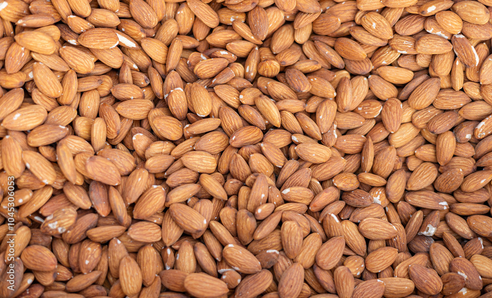 A large number of closely packed almonds with a light brown hue and textured surface. Relevant for food, agriculture, nutrition, or commerce discussions A large number of closely packed almonds with a light brown hue and textured surface. Relevant for food, agriculture, nutrition, or commerce discussions
