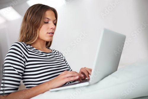 Typing, laptop and woman on sofa for freelancing, reading blog or relax in home lounge. Hybrid work, computer and online for research, writing email or language translation for social media platform photo