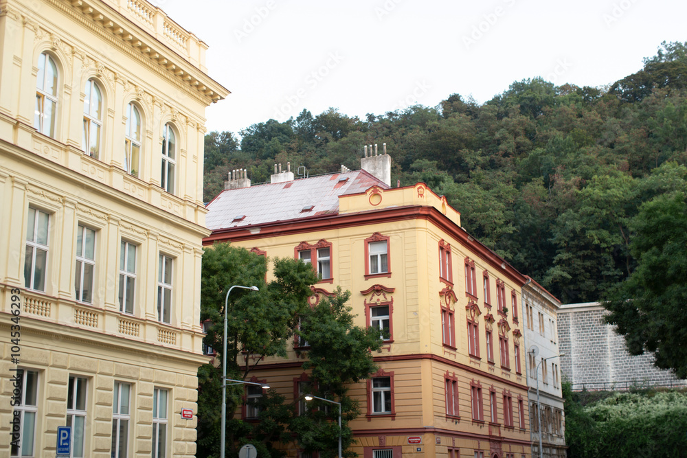 Obraz premium A long row of modern buildings stands tall, with lush green trees gracefully lining the background, creating a picturesque urban landscape