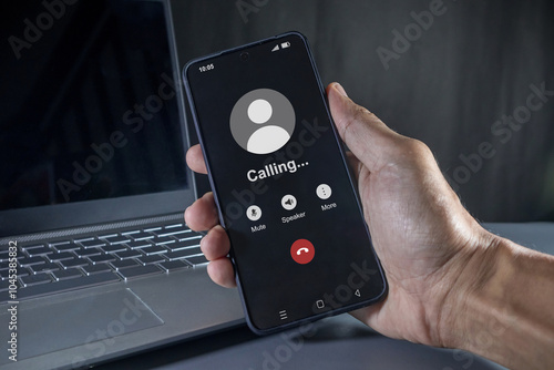 Hand holding a mobile phone with outgoing call screen. Call someone with a voice call.
