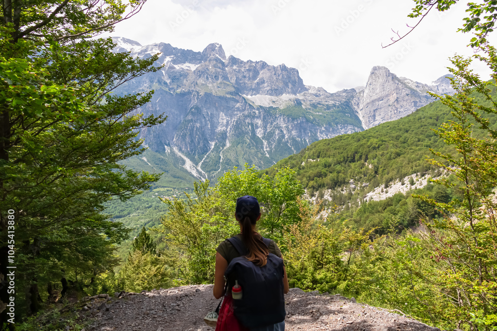 Hiker woman with panoramic of majestic mountain ridge massif Radohina, Albanian Alps (Accursed Mountains), Northern Albania. Scenic hiking trail from Valbona to Theth. Wanderlust in alpine wilderness Hiker woman with panoramic of majestic mountain ridge massif Radohina, Albanian Alps (Accursed Mountains), Northern Albania. Scenic hiking trail from Valbona to Theth. Wanderlust in alpine wilderness