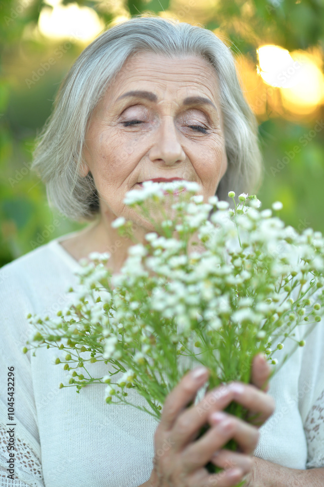 Portrait of a beautiful elderly woman with a bouquet of flowers in the park Portrait of a beautiful elderly woman with a bouquet of flowers in the park
