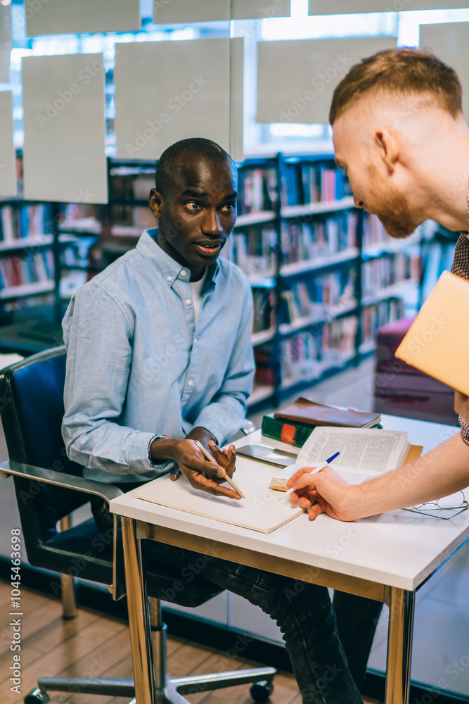 Multiracial team of student cooperating in library Multiracial team of student cooperating in library