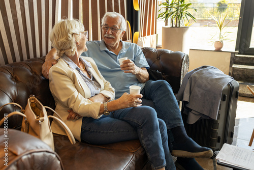 Mature couple sitting at the hall of hotel and wait for room key after registration in hotel for vacation