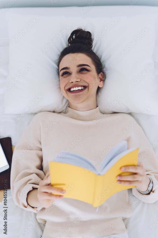 Woman lying with book and smartphone in bed Woman lying with book and smartphone in bed