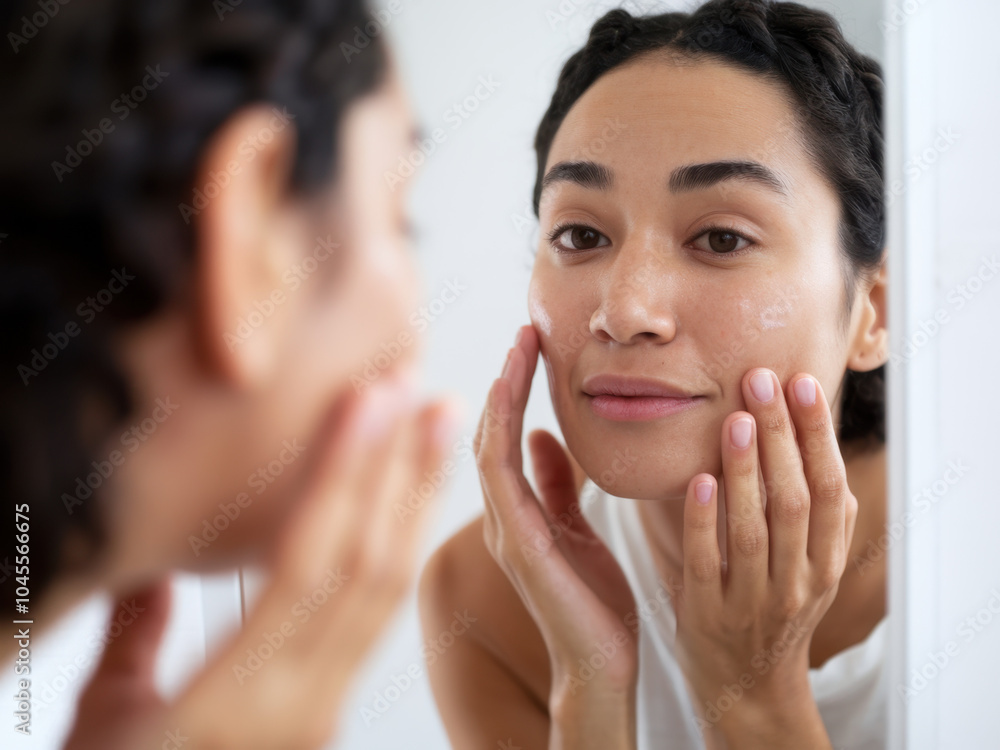 A woman examines her skin in a mirror, reflecting on her skincare routine with a thoughtful expression. A woman examines her skin in a mirror, reflecting on her skincare routine with a thoughtful expression.
