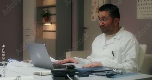 Wallpaper Mural The doctor is talking on a video chat on a laptop sitting at a table in the medical office at the clinic Torontodigital.ca