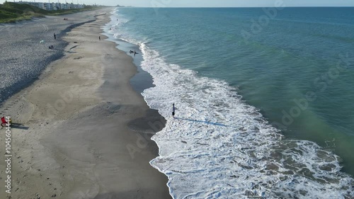 Aerial view of people on Floridana beach with foamy waves on a sunny day in Brevard, Florida, USA photo