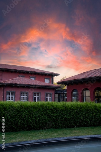 Huge Red Villa with Tall Shrubs at Sunset photo