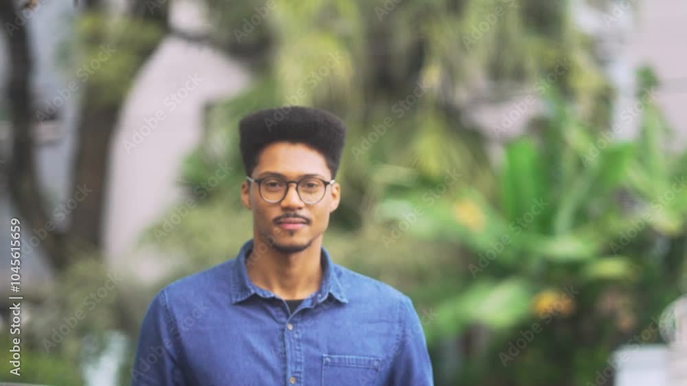 Smiling African American man in glasses as the camera slowly focuses on his face. Relaxed individual in a denim shirt enjoying an outdoor moment with a cheerful expression. Smiling African American man in glasses as the camera slowly focuses on his face. Relaxed individual in a denim shirt enjoying an outdoor moment with a cheerful expression.