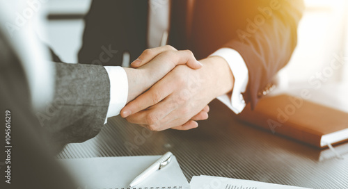 Unknown businessman shaking hands with his colleague or partner above the desk in sunny office, close-up