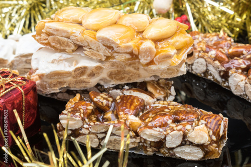 Different types of turrón (nougat), a traditional Christmas sweet in Spain, with some Christmas decoration, on a black surface. photo