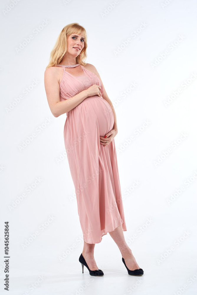 Woman in pink dress posing for photo. She is pregnant and wearing necklace. Mother love concept. Woman in pink dress posing for photo. She is pregnant and wearing necklace. Mother love concept.