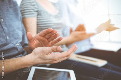 Business people clapping at meeting or conference, close-up of hands. Group of unknown businessmen and women in sunny office