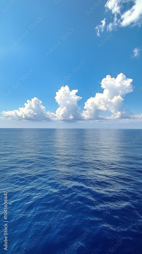 Calm ocean waters reflect the sky on a sunny day with scattered clouds Calm ocean waters reflect the sky on a sunny day with scattered clouds