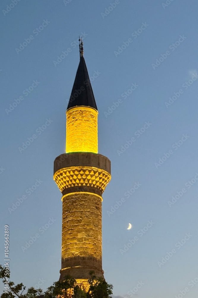 A lighted up minaret of an old mosque at night in the old town of antalya, Turkey