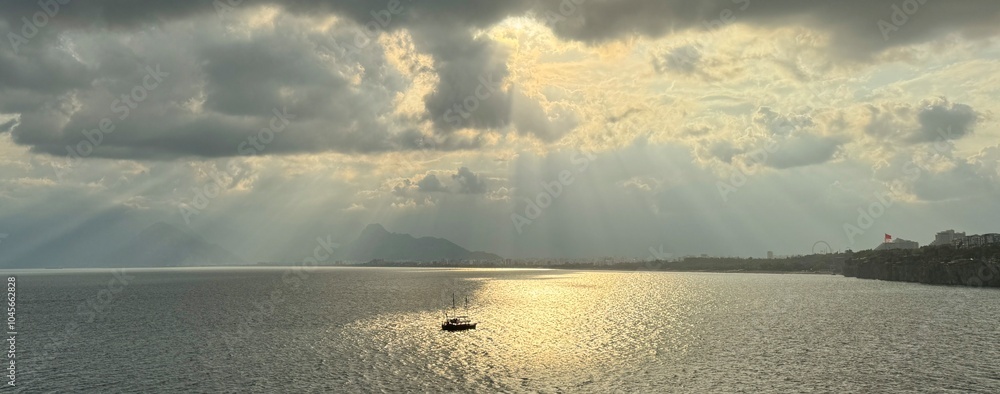 Beautiful sky with sun rays shining on the boat in the Mediterranean Sea in Antalya, Turkey