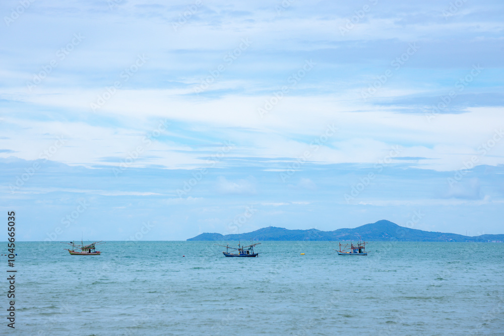 Serene Seascape: A tranquil scene of three fishing boats dotting the vast blue expanse of the ocean, with a distant island silhouetted against a cloudy sky. The image evokes a sense of peace. Serene Seascape: A tranquil scene of three fishing boats dotting the vast blue expanse of the ocean, with a distant island silhouetted against a cloudy sky. The image evokes a sense of peace.