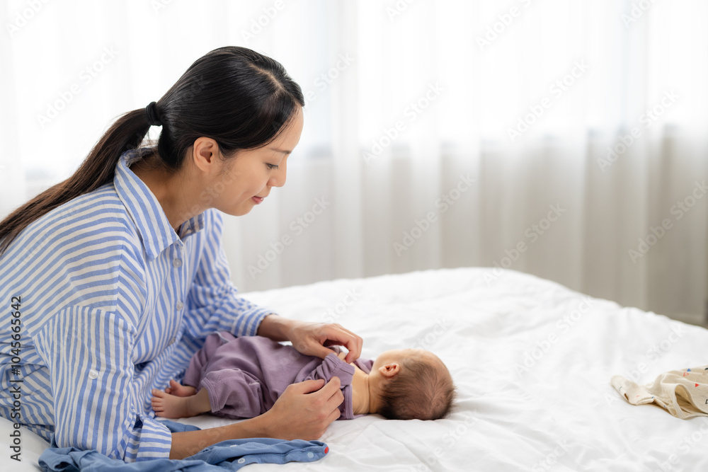 Asian mother help her new born baby to change his clothes Asian mother help her new born baby to change his clothes
