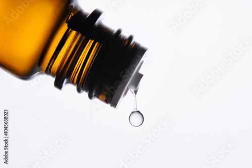 A drop of antihistamine or essential oil drips from a bottle. Close-up.