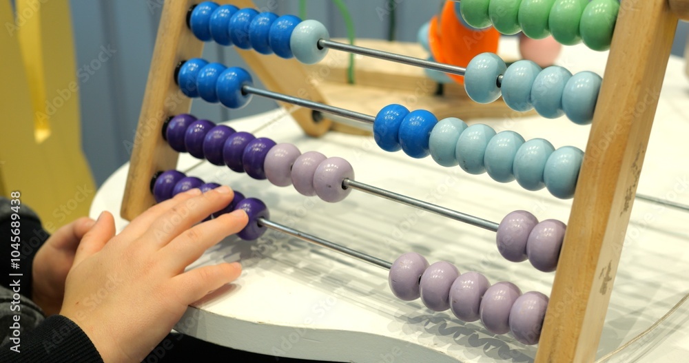 Little child solves maths tasks moving colorful beads on abacus at desk closeup. Toddler boy learns to count with old-fashioned device in preschool class Little child solves maths tasks moving colorful beads on abacus at desk closeup. Toddler boy learns to count with old-fashioned device in preschool class