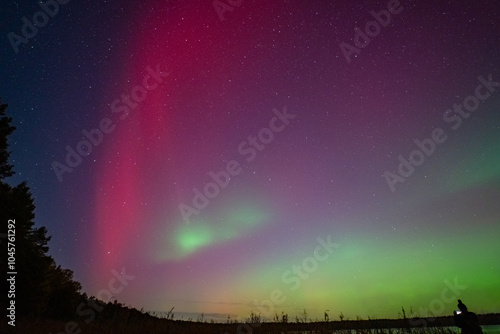 Northern Lights, Aurora Borealis. Night sky by the lake, geomagnetic storm G4