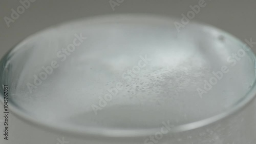 White powder is poured into a glass beaker with water on black background, medicine medical concept, macro, close up
