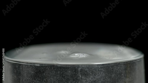 White powder is poured into a glass beaker with water on black background, medicine medical concept, macro, close up