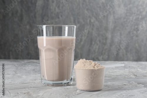 Delicious protein shake in glass and scoop with powder on grey table