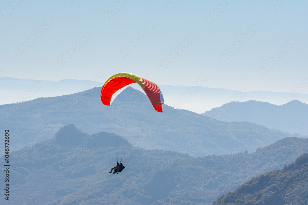 Flying paraglider in sky over mountains ridge Flying paraglider in sky over mountains ridge