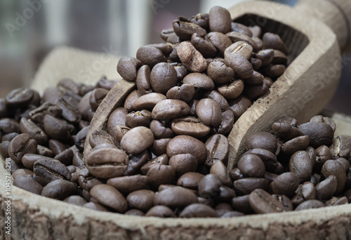 Coffee beans in wooden scoop on round wooden bowl. Alternative coffee for living life concept, Space for text, Selective focus.