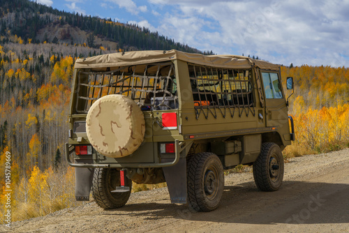 Vintage military vehicle traveling on the mountain roads in the fall with yellow aspen trees in the background photo