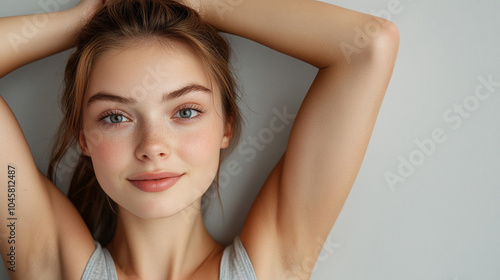 Woman with long brown hair and a tan complexion stands with her arms outstretched. She has a bright smile on her face and her eyes are looking up towards the sky. Concept of freedom and openness