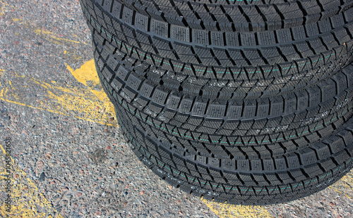 Identical winter tires with aggressive tread patterns are stacked on the highway. Same studless tires stock photo
 photo