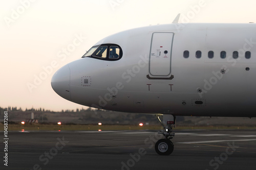 White passenger airplane along airport runway at dusk