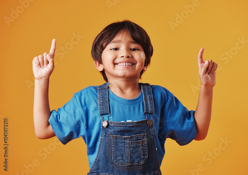 Japanese kid, boy and pointing in studio background for fashion with fun, outfit and swag in Japan. Male person, child and smile or happy on portrait in confidence with trendy clothes and style