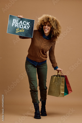 Studio shot of happy woman shopping on Black Friday and looking at camera. photo