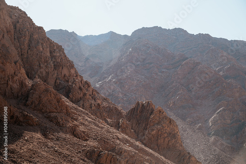 mountain range landscape. The mountains are characterized by sharp rocky outcroppings and steep slopes covered with rocks and little vegetation. The colors of the mountains range from dark brown to li