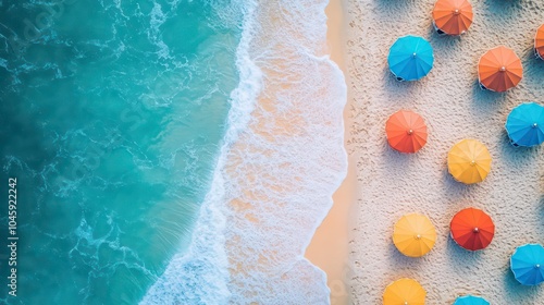 An aerial view of colorful beach umbrellas on a sandy beach next to a turquoise ocean.