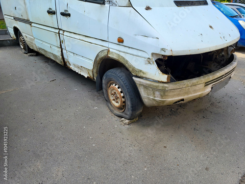 An old white rusty car with flat wheels. photo