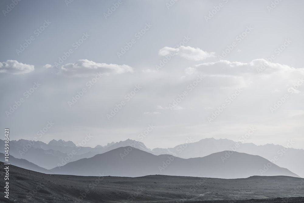Panoramic minimalist landscape of mountain ranges in Pamir in the Tien Shan Mountains in Tajikistan, silhouette of mountain peaks, landscape for the background Panoramic minimalist landscape of mountain ranges in Pamir in the Tien Shan Mountains in Tajikistan, silhouette of mountain peaks, landscape for the background