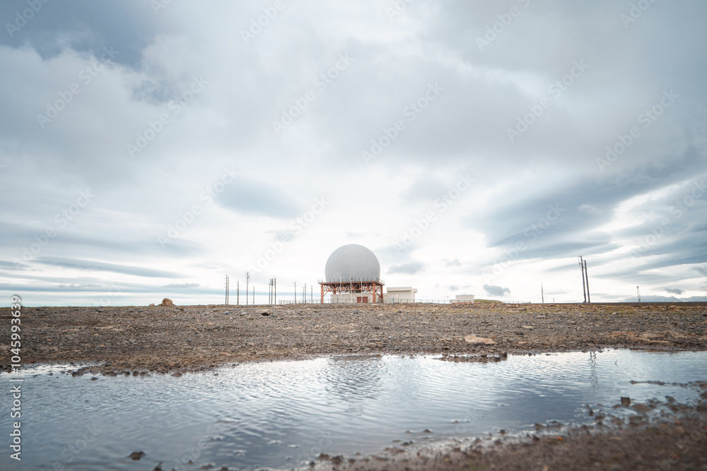 Obraz premium A radar station sits atop the rocky cliffs of Bolafjall mountain in Iceland's Westfjords, near Bolungarvik.