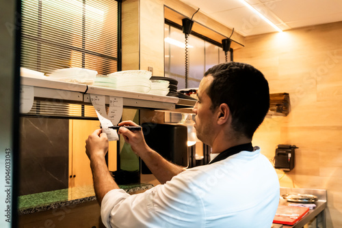 Chef reviewing orders in a busy restaurant kitchen photo