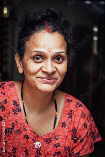 An Indian woman wearing a night dress, smiling and looking at the camera after completing the pooja of Karva Chauth. photo